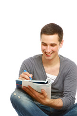 A young handsome college guy sitting on the floor and studying