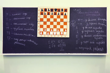 Chess stand on chessboard at blackboard of chess club