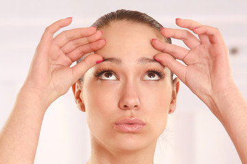 A young woman checking wrinkles on her forehead, closeup