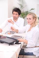 Fototapeta premium Couple cooking meat on a tabletop electric plate