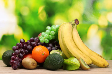 Assortment of exotic fruits on wooden table on green background