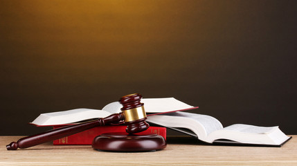 Judge's gavel and books on wooden table on brown background