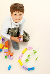 A boy playing with blocks, sitting on the floor, top view