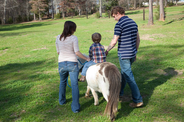 Parents taking their son on a pony ride