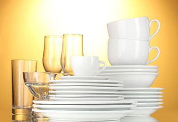 empty bowls, plates, cups and glasses on yellow background