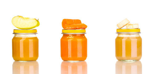 Jars of baby puree with spoon isolated on white