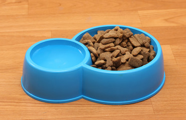 dry dog food and water in blue bowl on the floor