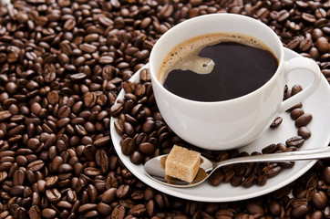Cup of coffee sitting on a pile of coffe beans