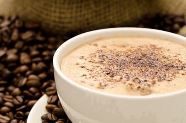 Cup of cappuccino arranged with coffee beans and bag