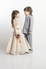 Fototapeta na wymiar Dwa piękne mali chłopcy i dziewczynki w sukniach ślubnych