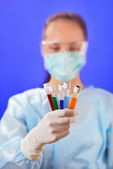 Doctor (woman) analyzing medical test tubes on blue background