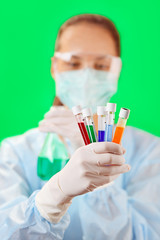 Medical test tubes with fluid sample in doctor's hand on green b