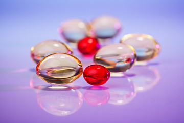 Pills (capsules) of cod-liver oil on violet, macro view with sel