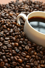 A cup of coffee on coffee beans, closeup