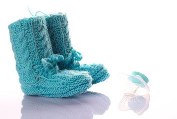 gestrickte Babyschuhe mit einem hellblauen Schnuller