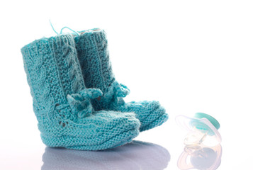 Gestrickte Kinderschuhe mit einem hellblauen Schnuller