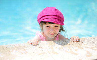 Cute little girl on the edge of swimming pool