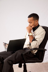 Handsome black man sitting, hand on chin thinking