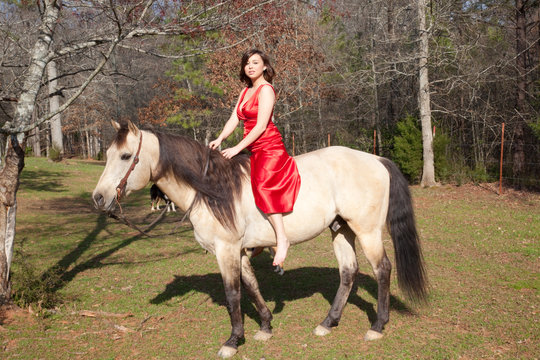 Woman in a red dress, riding a horse bareback