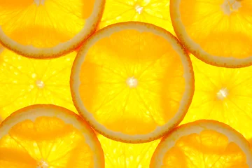 Fotobehang Plakjes fruit Sinaasappelschijfjes achtergrond / macro / verlichte achtergrond