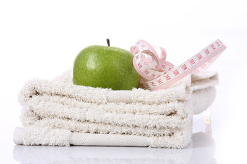 A green apple and a measuring tape on a towel