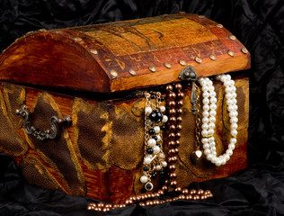 Vintage wooden treasure trunk with jewelry on black background