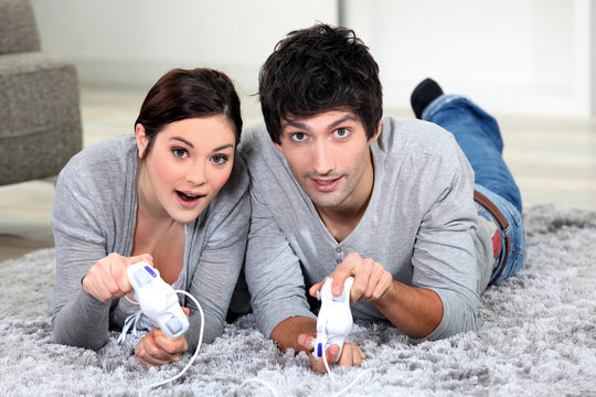 Couple laying on rug playing video games