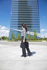 businesswoman walking next to skyscraper