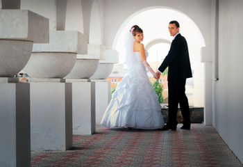 The bride and groom looked, standing  in a white arch