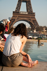 jeune femme assise devant la tour eiffel à Paris