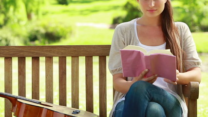 Woman reading a book with a guitar next to her - Powered by Adobe