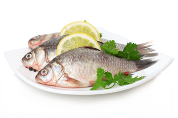 Fresh fishes with lemon and parsley on plate isolated on white