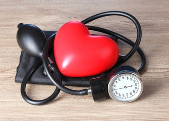 Black tonometer and heart on wooden background