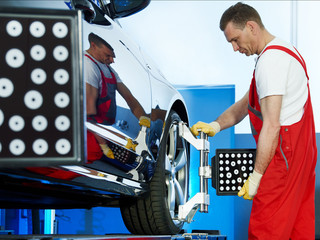 Motor mechanic is doing axle alignment in a garage
