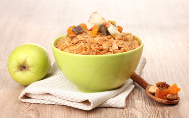 tasty cornflakes in bowl with dried fruits and apple