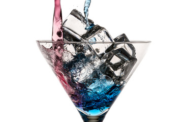 Blue and red liqueur poured into a glass with ice cubes on white