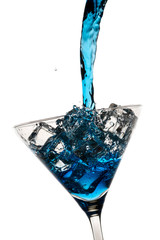 Blue liqueur poured into a martini glass with ice cubes on white