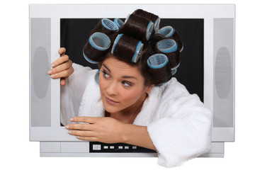 Woman wearing hair rollers escaping from television