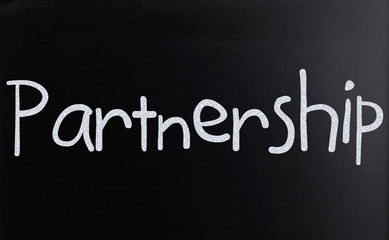 The word "Partnership" handwritten with white chalk on a blackbo