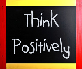 "Think Positively" handwritten with white chalk on a blackboard