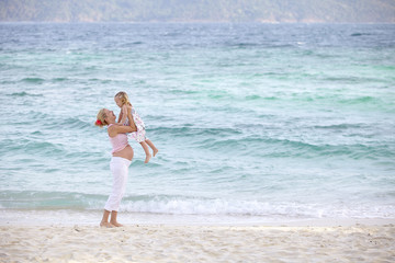 Fototapeta premium junge schwangere mutter mit ihrer tochter am strand