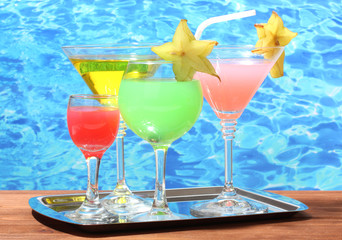 Glasses of cocktails on wooden table on blue sea background