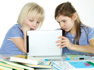 Two cute girlfriends learning with books and touchpad