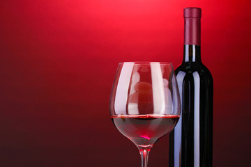 Bottle of great wine and wineglass on red background