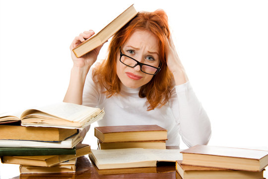 Beautiful red-haired girl in glasses reads book.