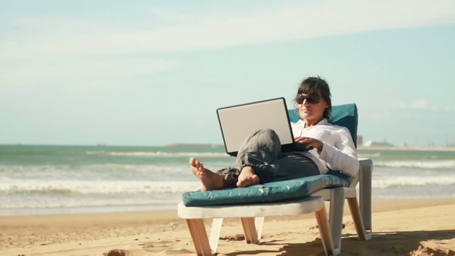 Businesswoman finishing work on laptop and relaxing on sunbed