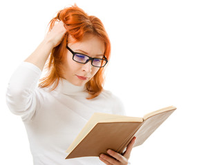 Beautiful red-haired girl in glasses reads book.