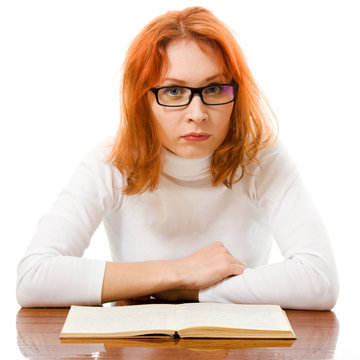 Beautiful red-haired girl in glasses reads book.