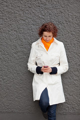 Frau an Wand schaut auf Handy