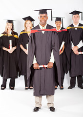 african male graduate with classmates at graduation